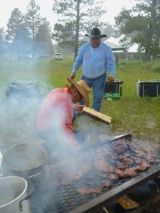 Malcolm Lehi and friend tend venison on the grill in the midst of an afternoon rainstorm (c) Gavin Noyes 
